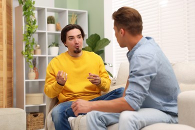 Photo of Friends having conversation on sofa at home