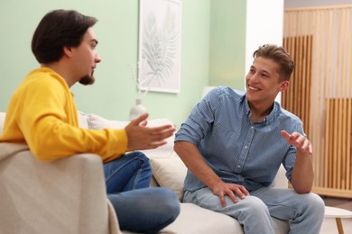 Photo of Friends having conversation on sofa at home