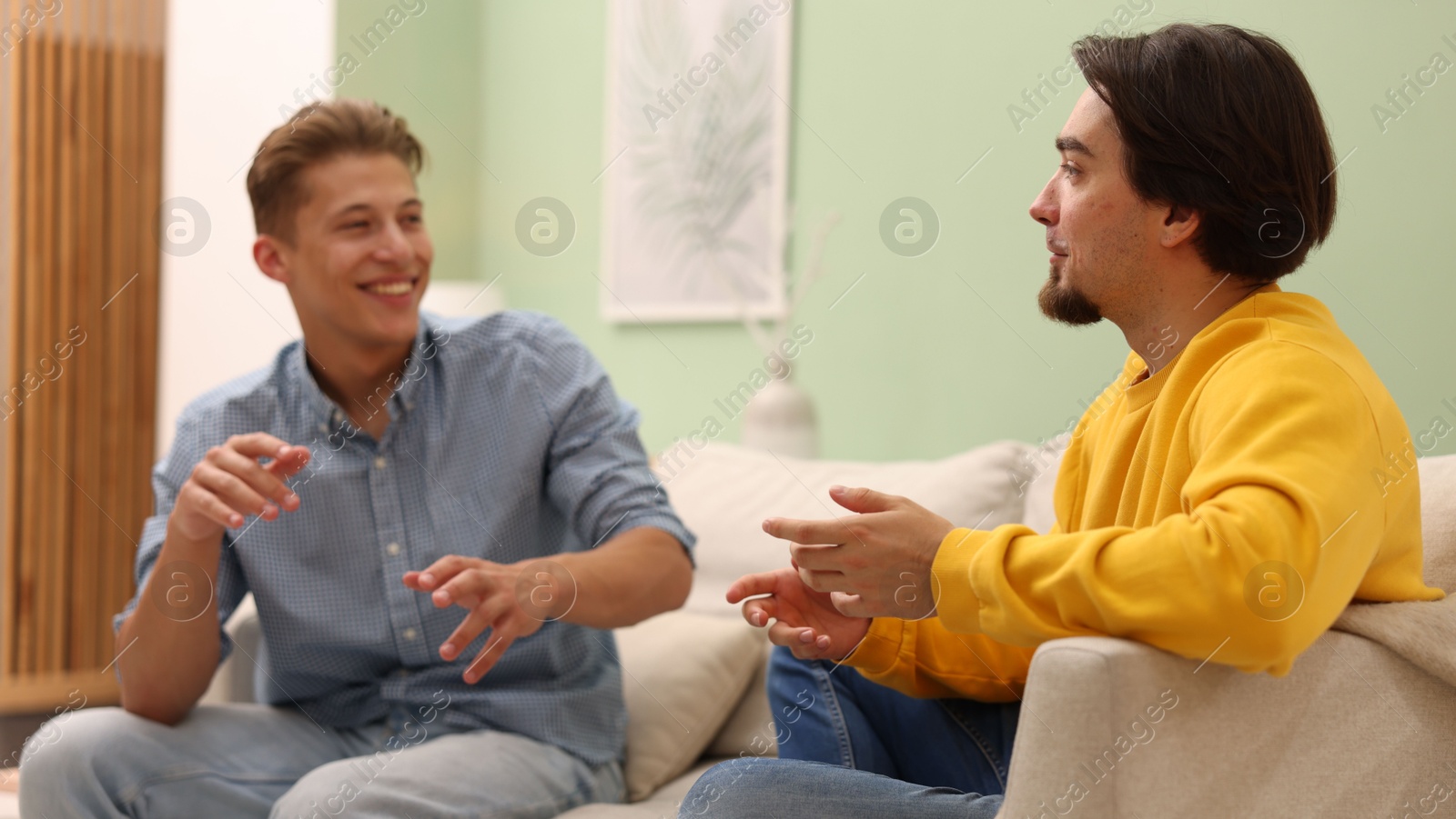 Friends having conversation on sofa at home Photo of Friends having conversation on sofa at home