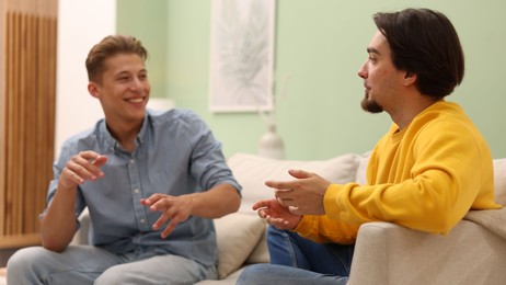 Photo of Friends having conversation on sofa at home