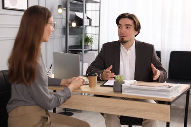 Photo of Coworkers discussing project together at desk in office