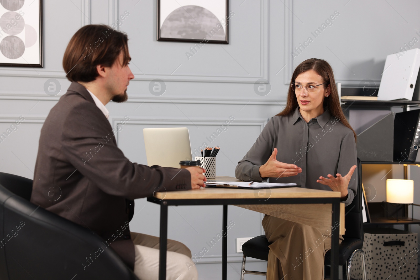 Coworkers discussing project together at desk in office Photo of Coworkers discussing project together at desk in office