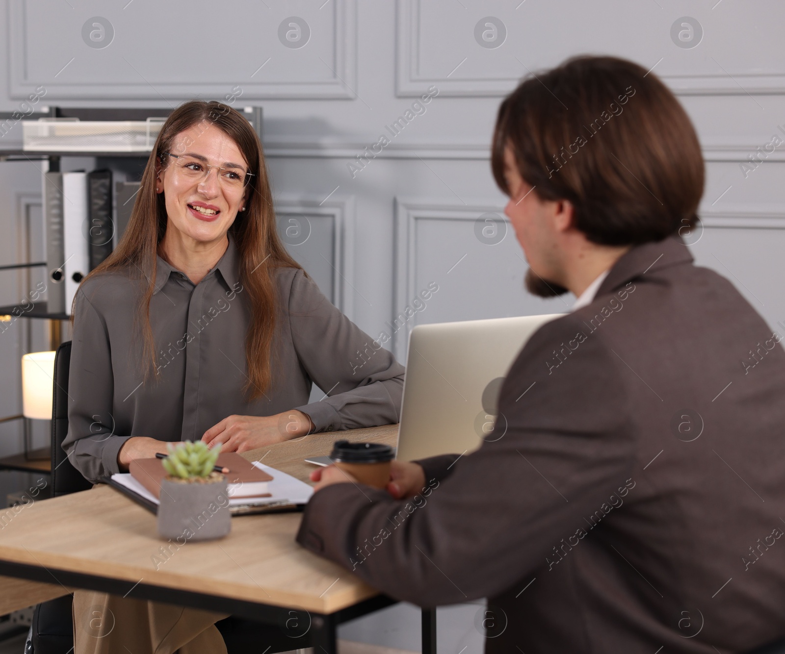 Photo of Coworkers discussing project together at desk in office