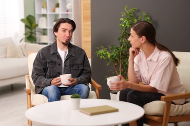 Photo of Woman and man talking while having tea at home