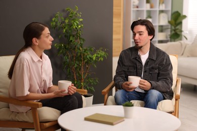 Photo of Woman and man talking while having tea at home