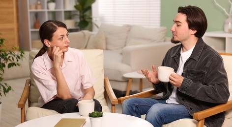 Photo of Woman and man talking while having tea at home