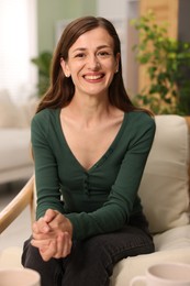 Photo of Smiling woman sitting in armchair at home