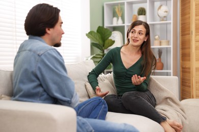 Photo of Woman and man talking on sofa at home