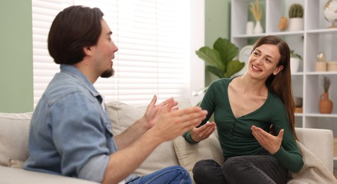 Photo of Woman and man talking on sofa at home