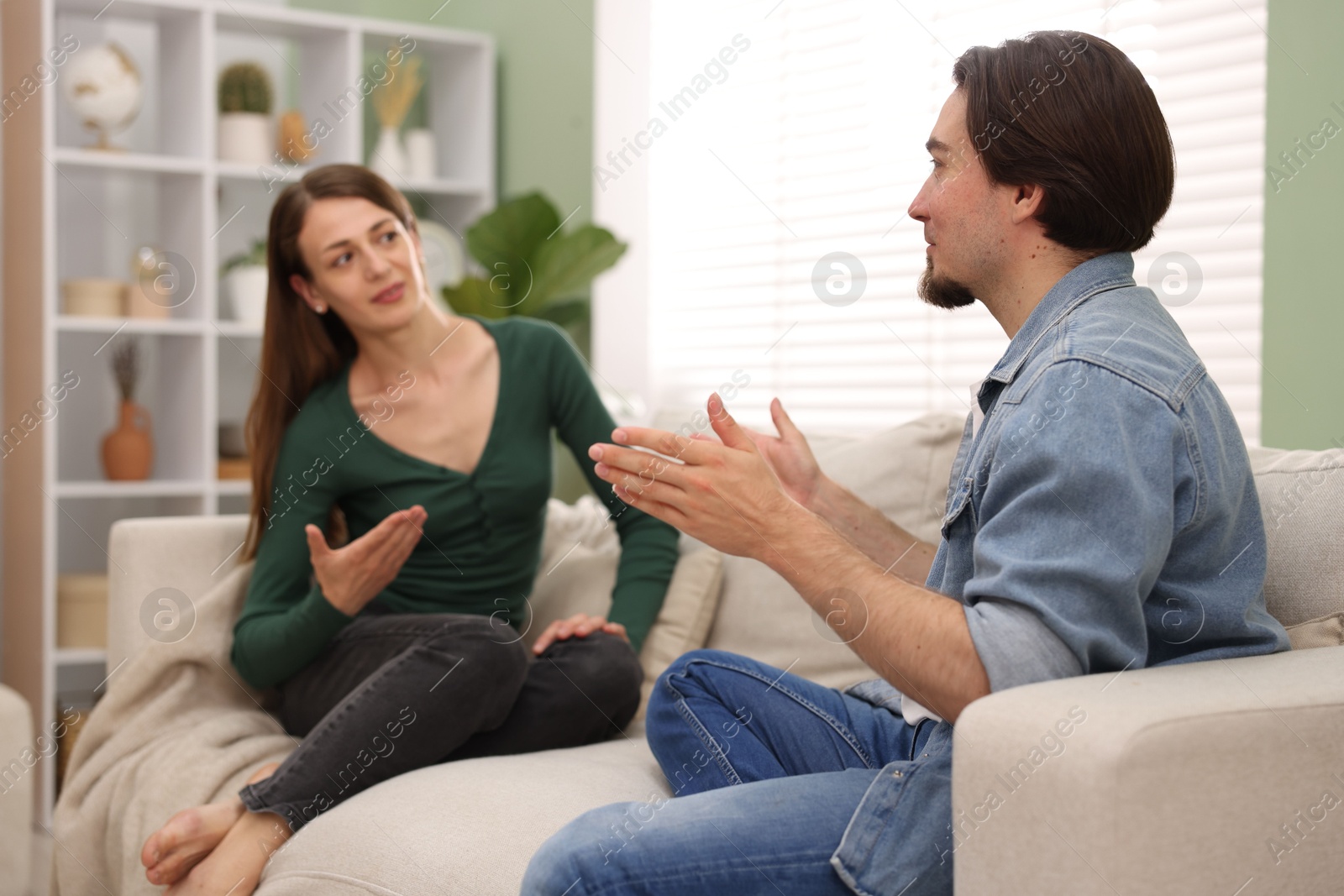 Photo of Woman and man talking on sofa at home