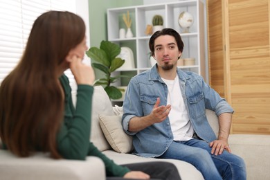 Photo of Woman and man talking on sofa at home