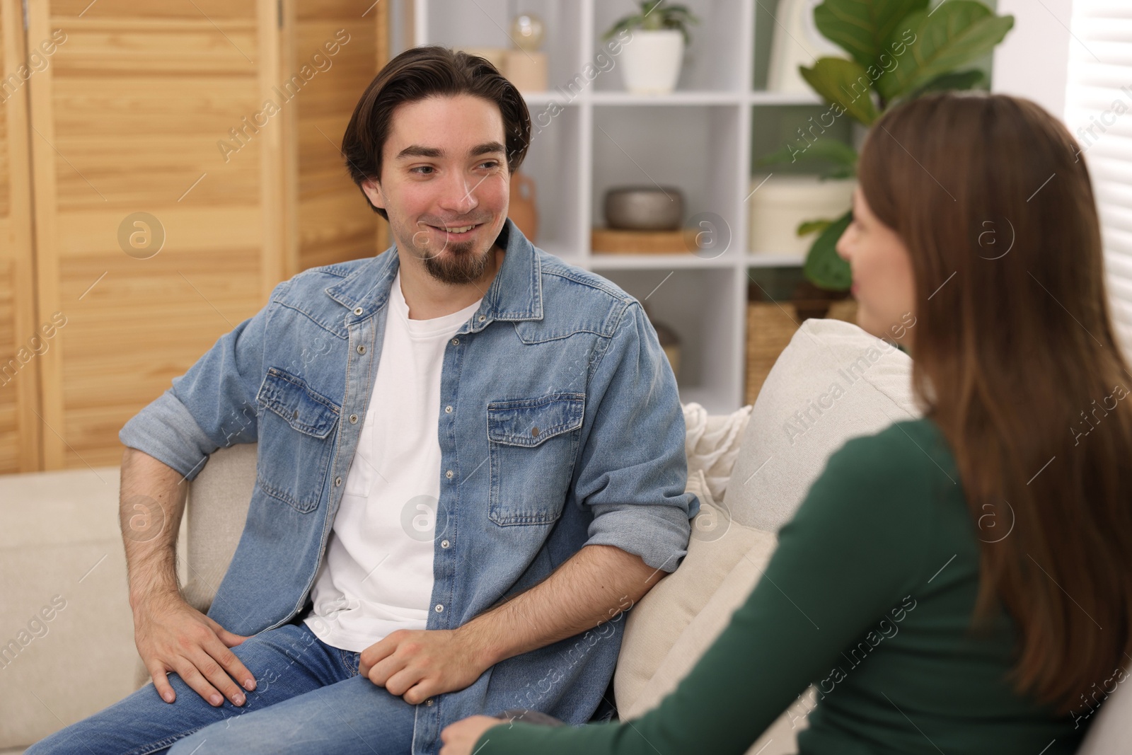 Photo of Woman and man talking on sofa at home