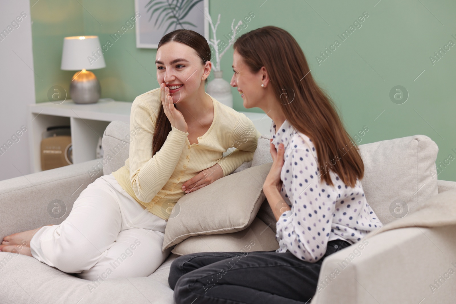 Friends having conversation on sofa at home Photo of Friends having conversation on sofa at home