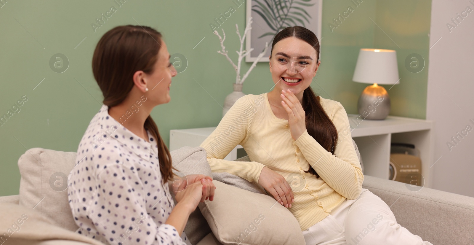 Friends having conversation on sofa at home Photo of Friends having conversation on sofa at home