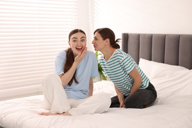 Photo of Friends gossiping during sleepover on bed at home