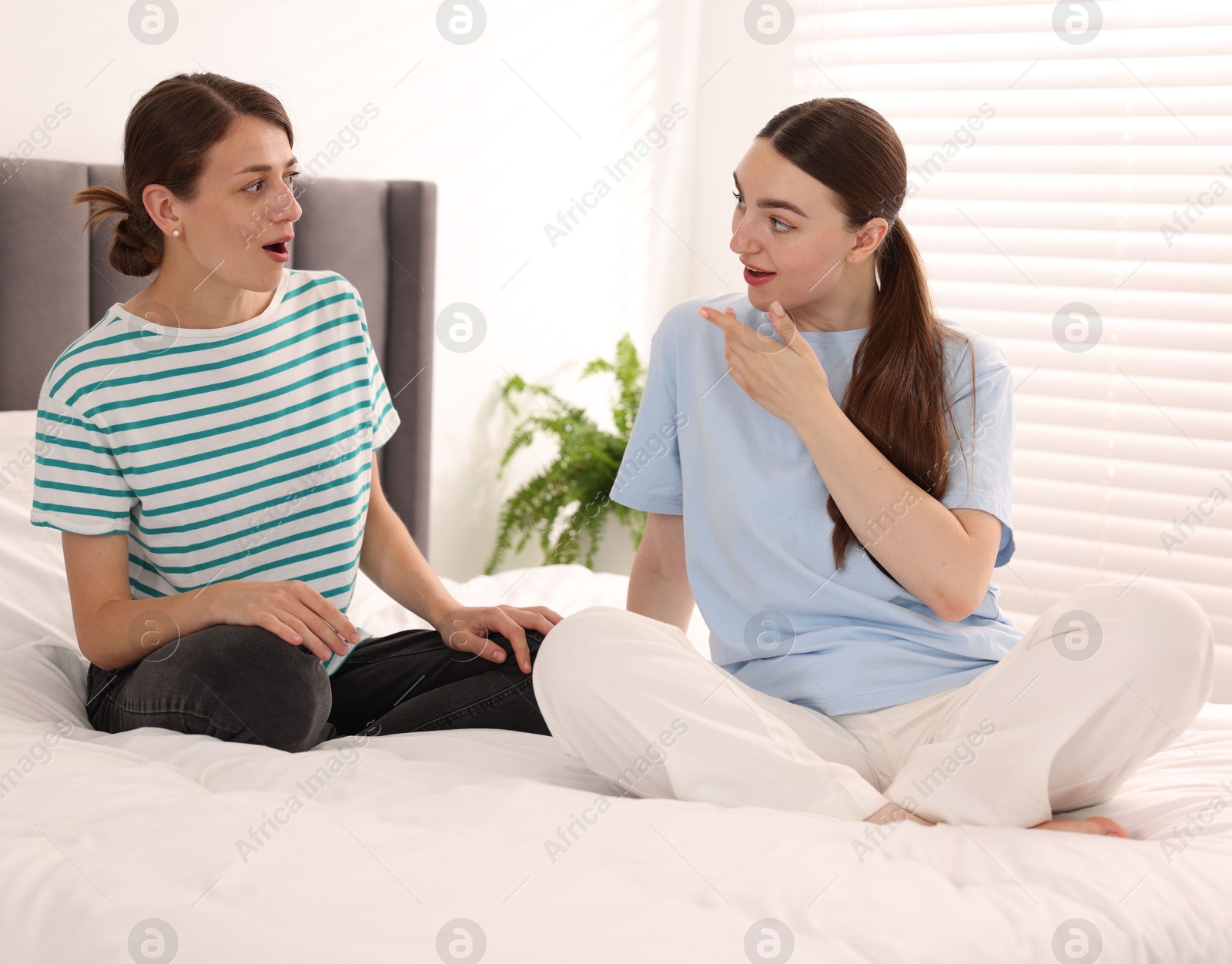 Friends gossiping during sleepover on bed at home Photo of Friends gossiping during sleepover on bed at home