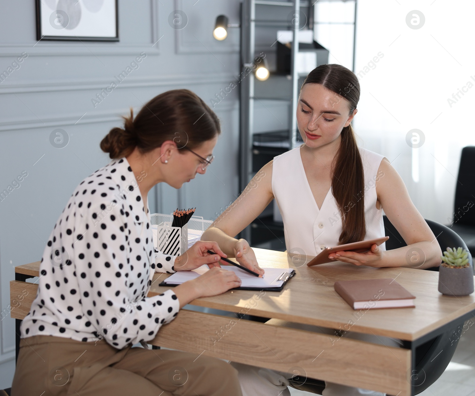 Photo of Coworkers discussing project together at desk in office