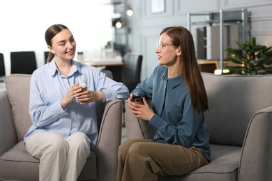 Photo of Coworkers talking during coffee break in armchairs at office