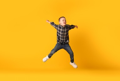 Photo of Cute little boy jumping on orange background