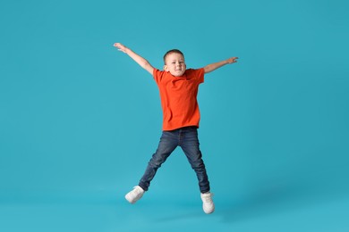 Photo of Cute little boy jumping on light blue background