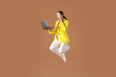Photo of Woman with laptop jumping on brown background