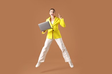 Photo of Woman with laptop jumping on brown background