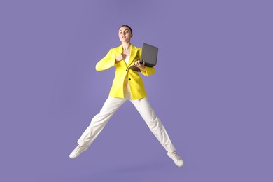 Photo of Woman with laptop jumping on purple background