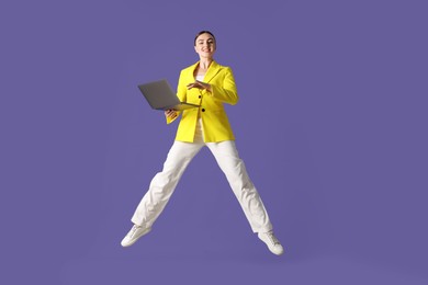 Photo of Woman with laptop jumping on purple background