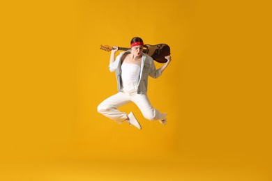 Photo of Woman with guitar jumping on orange background