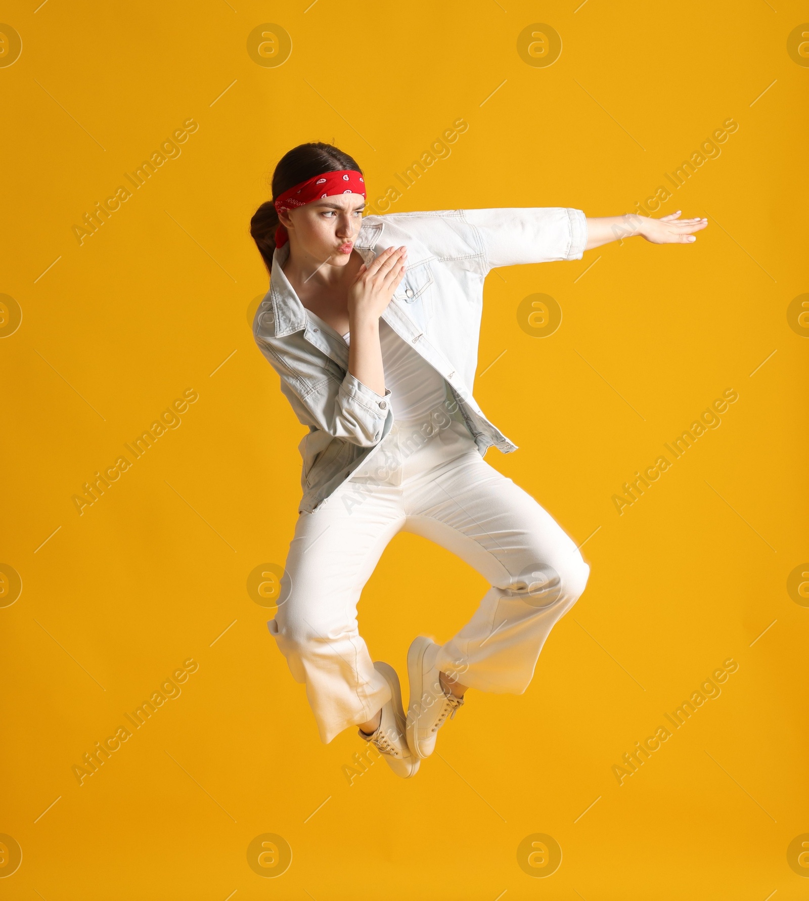 Woman in stylish outfit jumping on orange background Photo of Woman in stylish outfit jumping on orange background