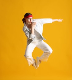Photo of Woman in stylish outfit jumping on orange background