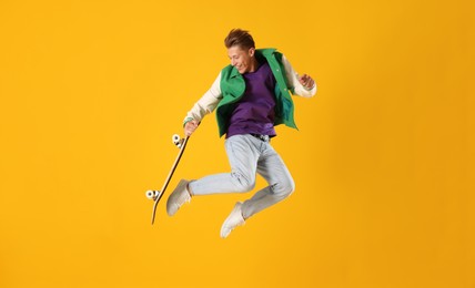 Photo of Man with skateboard jumping on orange background