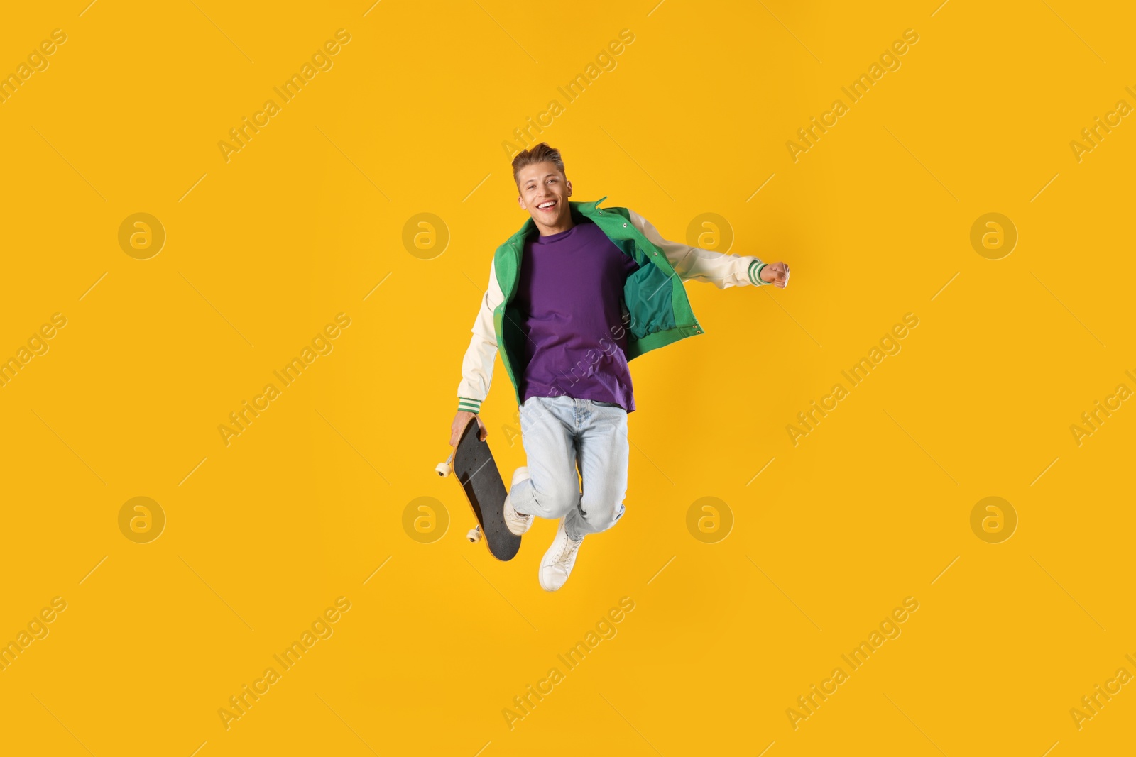 Man with skateboard jumping on orange background Photo of Man with skateboard jumping on orange background