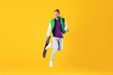 Photo of Man with skateboard jumping on orange background