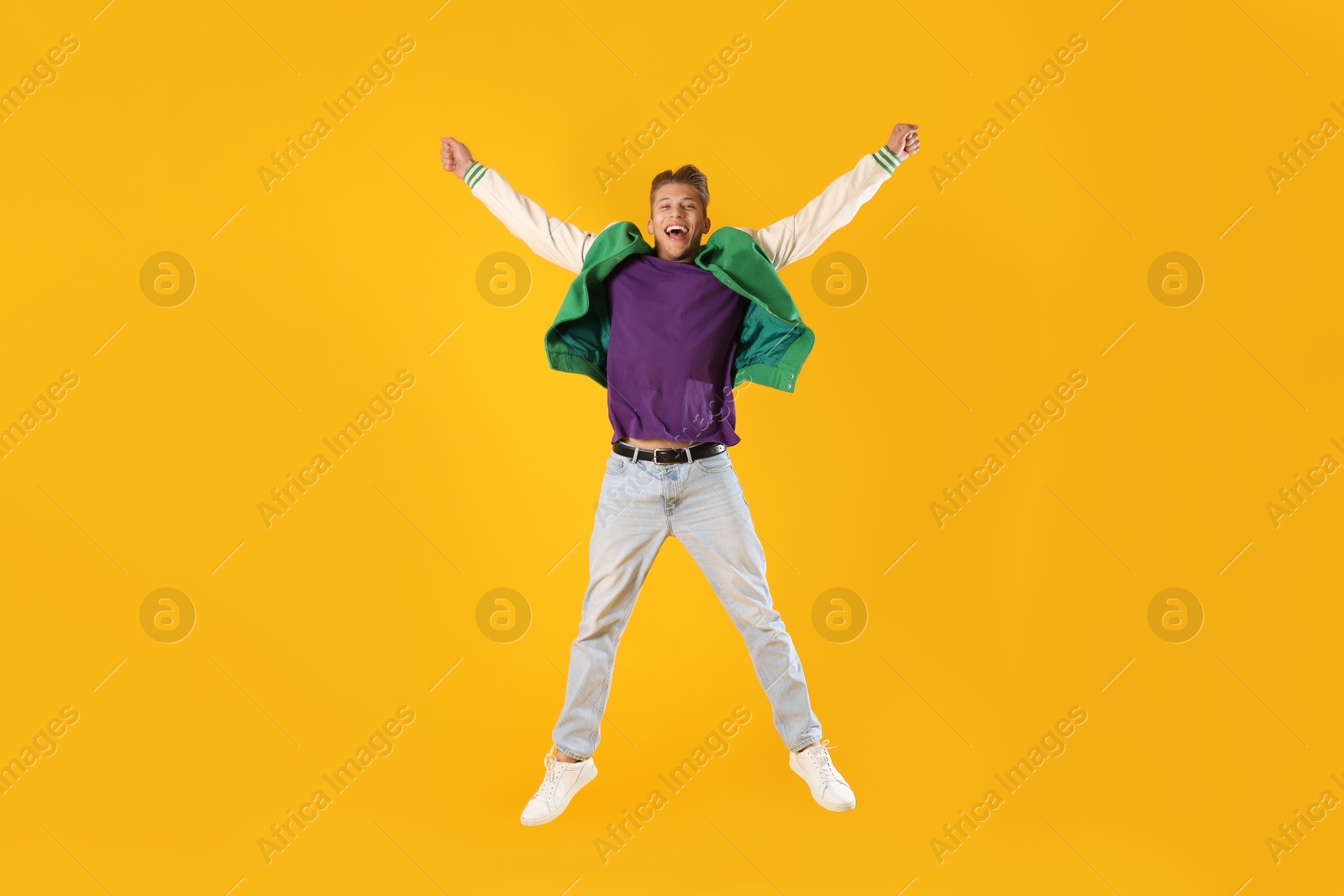 Man in stylish outfit jumping on orange background Photo of Man in stylish outfit jumping on orange background