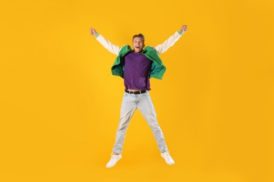 Photo of Man in stylish outfit jumping on orange background