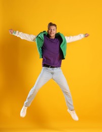 Photo of Man in stylish outfit jumping on orange background
