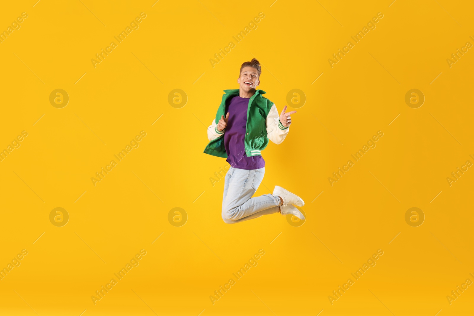 Man in stylish outfit jumping on orange background Photo of Man in stylish outfit jumping on orange background