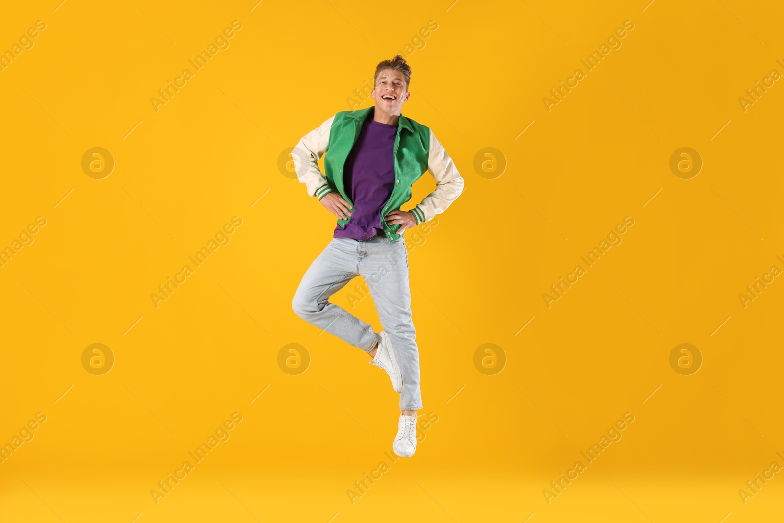 Man in stylish outfit jumping on orange background Photo of Man in stylish outfit jumping on orange background
