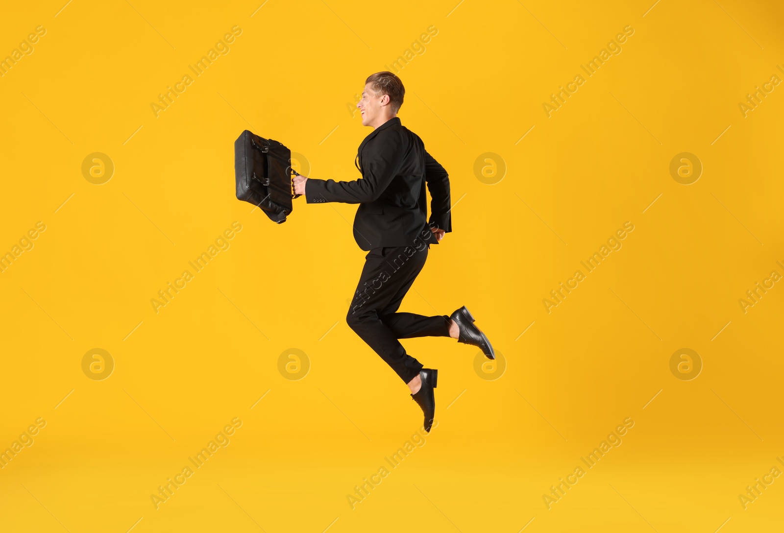 Businessman with briefcase jumping on orange background Photo of Businessman with briefcase jumping on orange background
