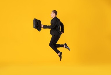 Photo of Businessman with briefcase jumping on orange background
