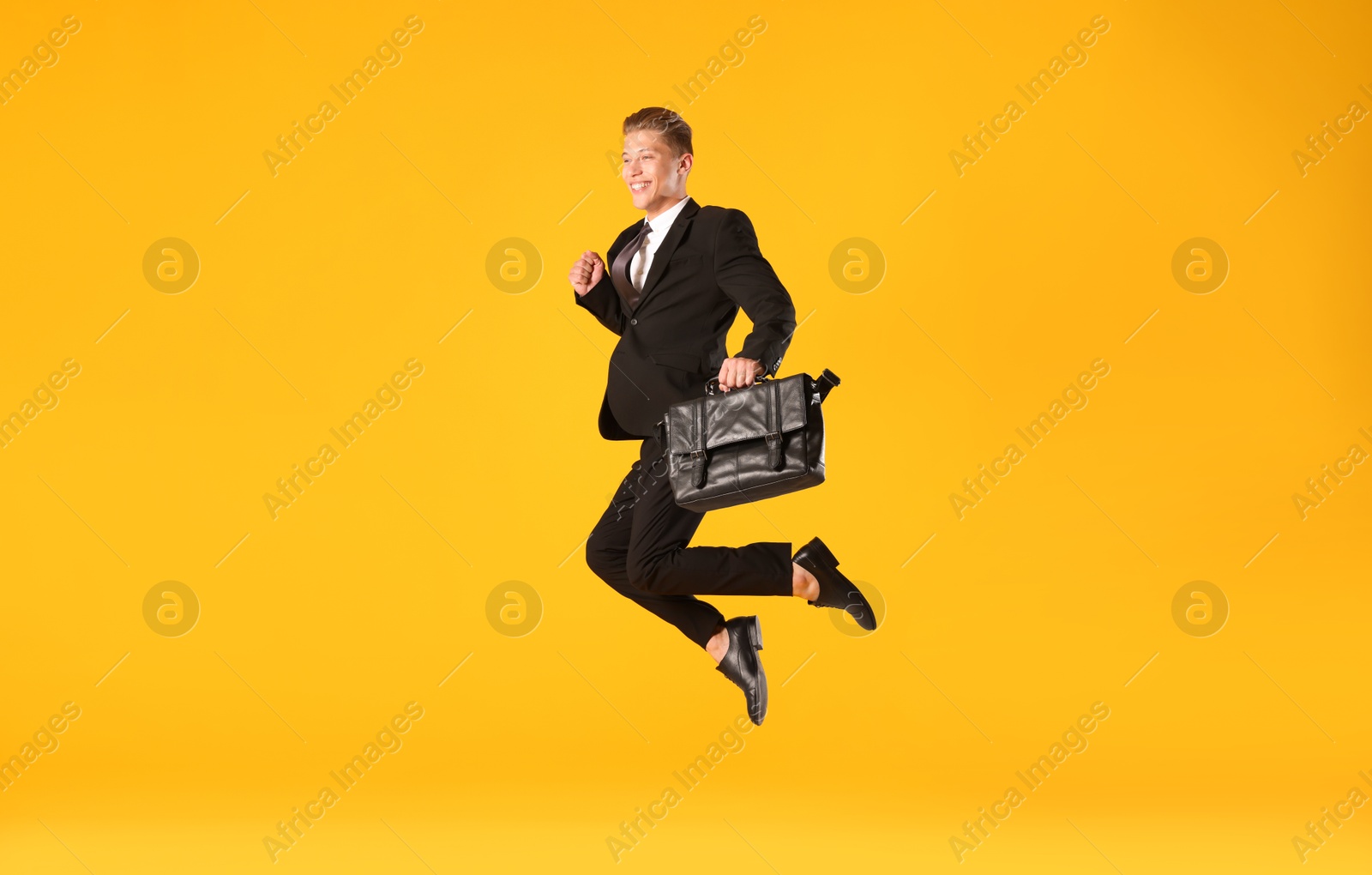 Businessman with briefcase jumping on orange background Photo of Businessman with briefcase jumping on orange background