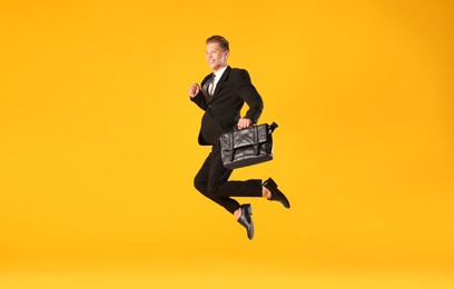 Photo of Businessman with briefcase jumping on orange background