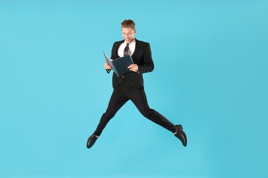 Photo of Businessman with folder jumping on light blue background