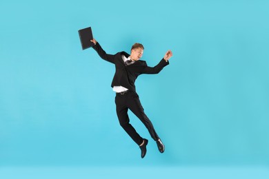 Photo of Businessman with folder jumping on light blue background