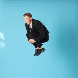 Photo of Happy businessman jumping on light blue background