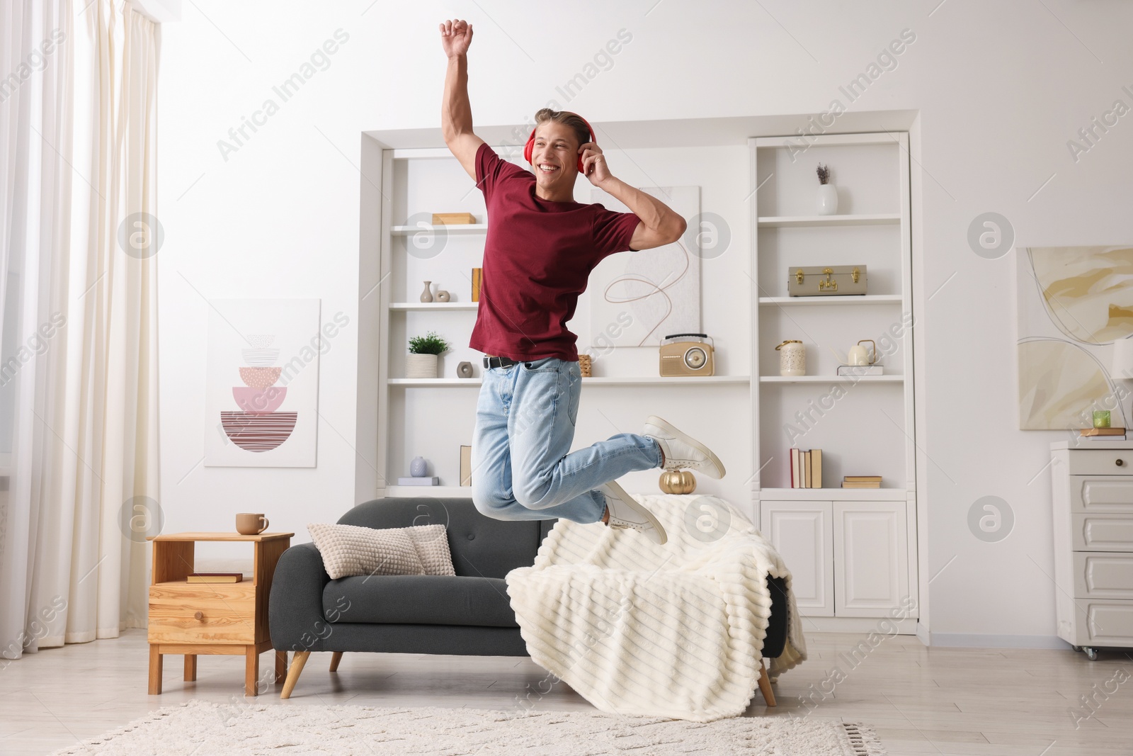 Happy man jumping while listening to music at home Photo of Happy man jumping while listening to music at home