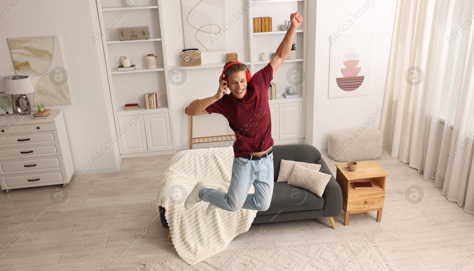 Happy man jumping while listening to music at home Photo of Happy man jumping while listening to music at home