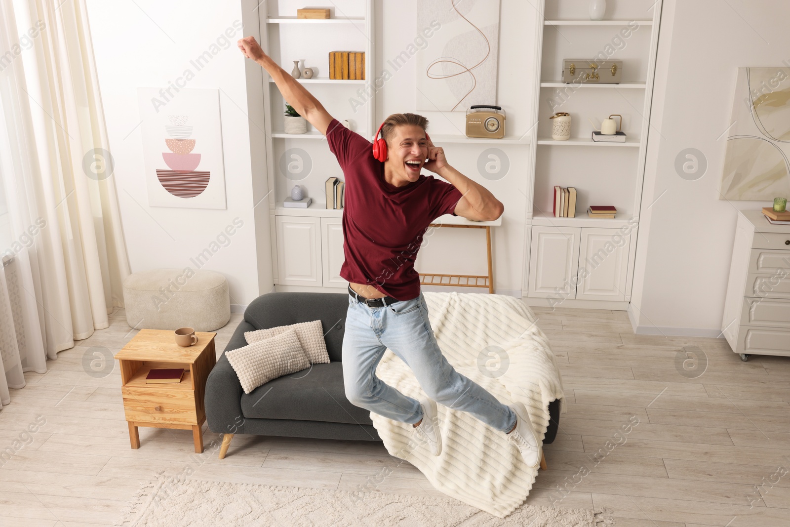 Happy man jumping while listening to music at home Photo of Happy man jumping while listening to music at home