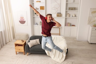 Photo of Happy man jumping while listening to music at home